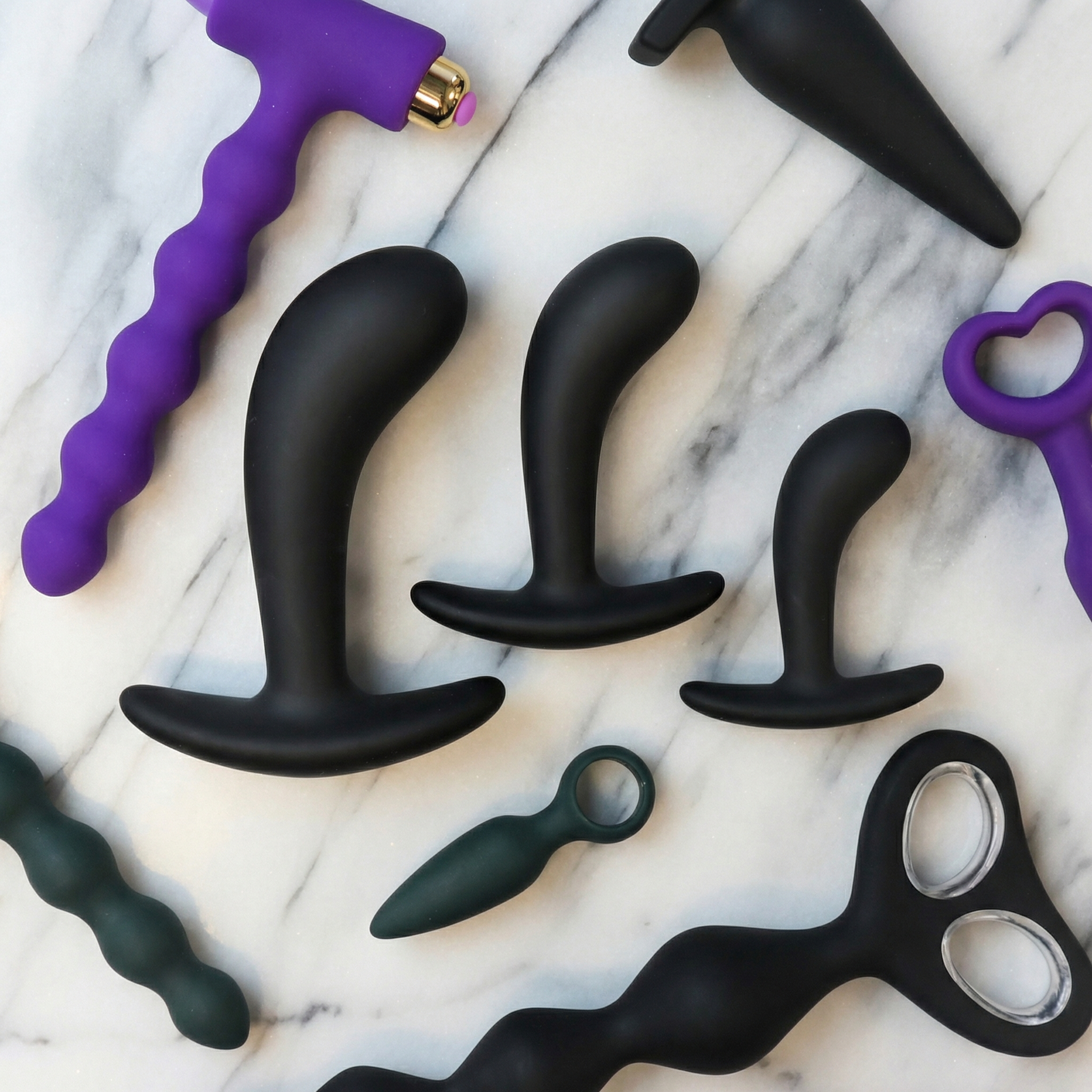 Assortiment buttplugs en anal beads voor beginners op een elegante achtergrond met zachte kleuren en stijlvolle presentatie