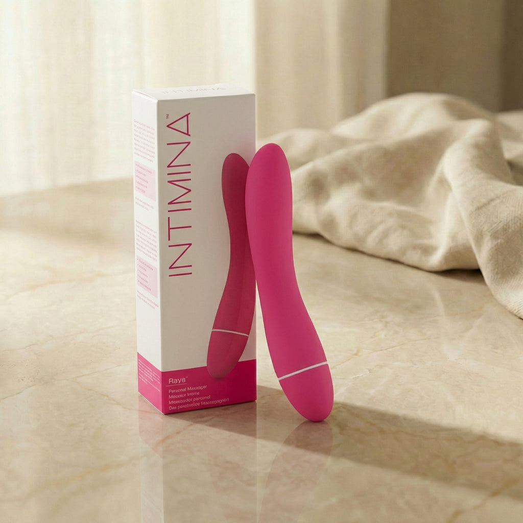 Roze Intimina Raya persoonlijke massager naast wit-roze verpakking op marmeren ondergrond