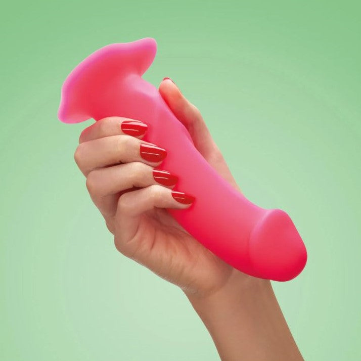 Hand met rode nagels houdt The Boss dildo in roze vast, toont flexibel siliconen
